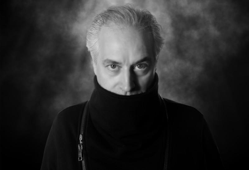 Wesley Stace with his mouth covered by a turtleneck sweater pulled over his lower face