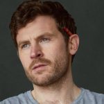 Comedian George Lewis looking into the distance. He has a crayon behind his ear