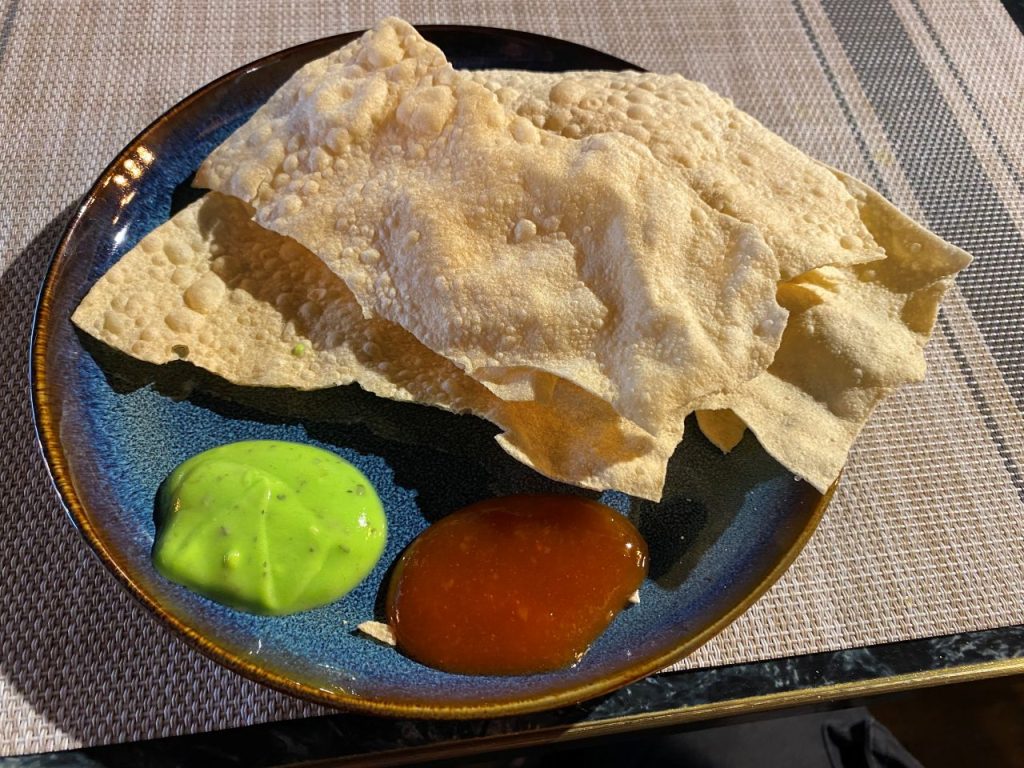 A poppadom on a plate with sauces