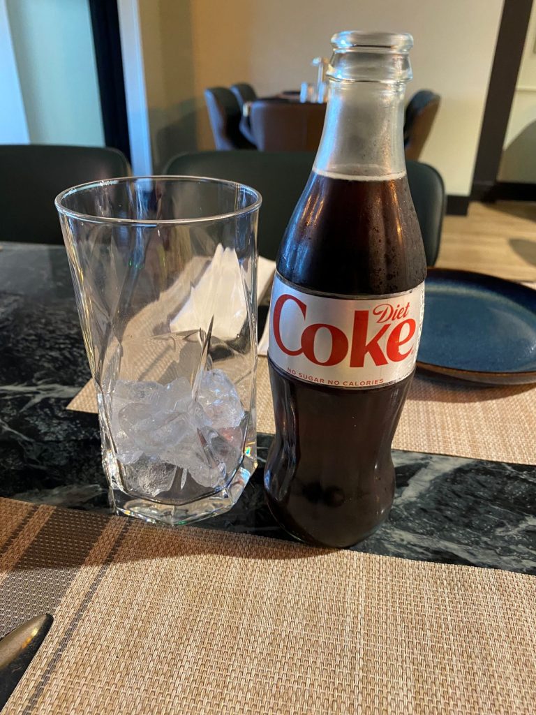 A glass with ice in and a bottle of Diet Coke