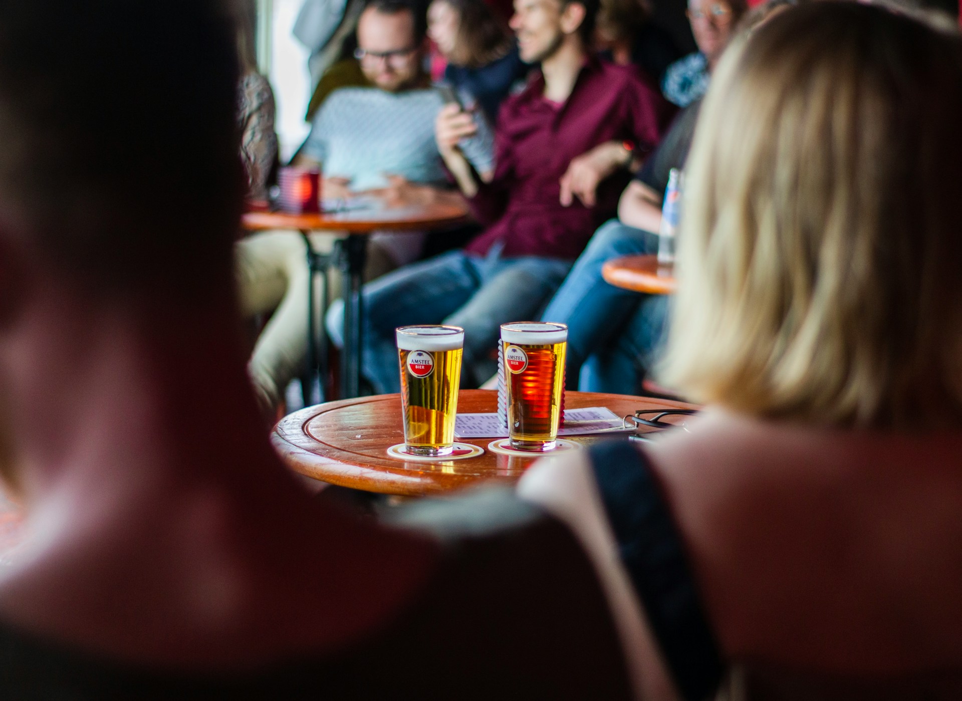 People in a pub with drinks on a small round table