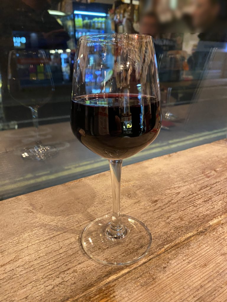 A glass of red wine sitting on the shelf of Mama's Way in Duke Street Reading. The dark night can be seen through the window