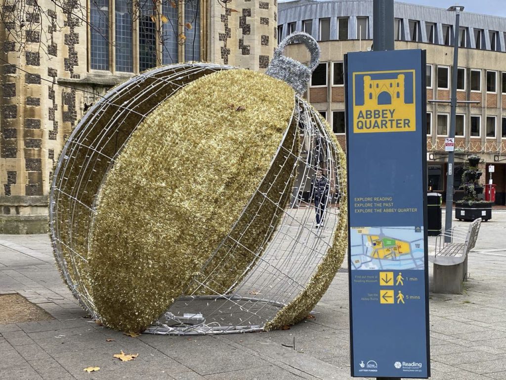 A giant bauble, made of gold tinsel, on the street next to a sign saying Abbey Quarter