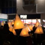 People holding tepee-style lanterns outside a sign that reads Broad St. Mall, the name of a shopping centre in Reading