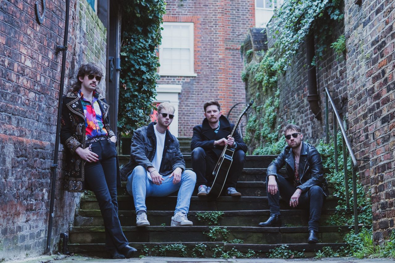 The Liaisons band sitting on steps in an outdoor venue