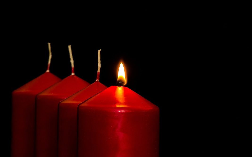 Four Advent candles. Only the first candle is lit to mark the first Sunday in Advent. The candles are red