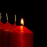 Four Advent candles. Only the first candle is lit to mark the first Sunday in Advent. The candles are red