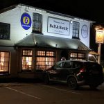The Bell and Bottle in School Green, Shinfield. The photo of the building's exterior is taken at night so it is lit up from the inside.