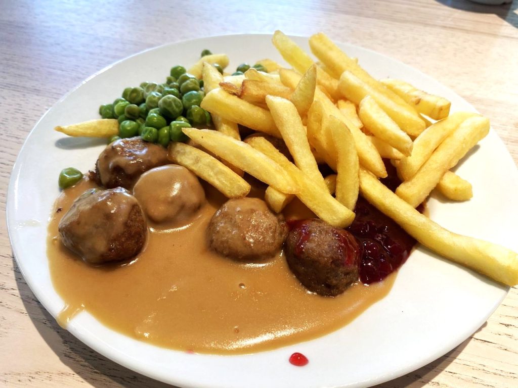 A plate of meatballs, chips and peas with IKEA's sauce