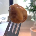An IKEA meatballs on a fork and covered in sauce