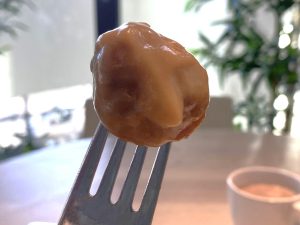 An IKEA meatball on a fork and covered in sauce