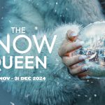 The marketing poster for The Snow Queen. In the top left is Reading Rep's logo. The Snow Queen is pictured holding a snow globe with a festive scene inside it. The poster is primarily blue in colour