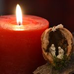 An Advent candle and a miniature crib. The candle is red and lit. The church of Christ Church in Reading is holding Advent services this Christmas