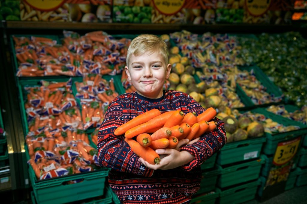 a boy holding a pile of carrots at Morrisons