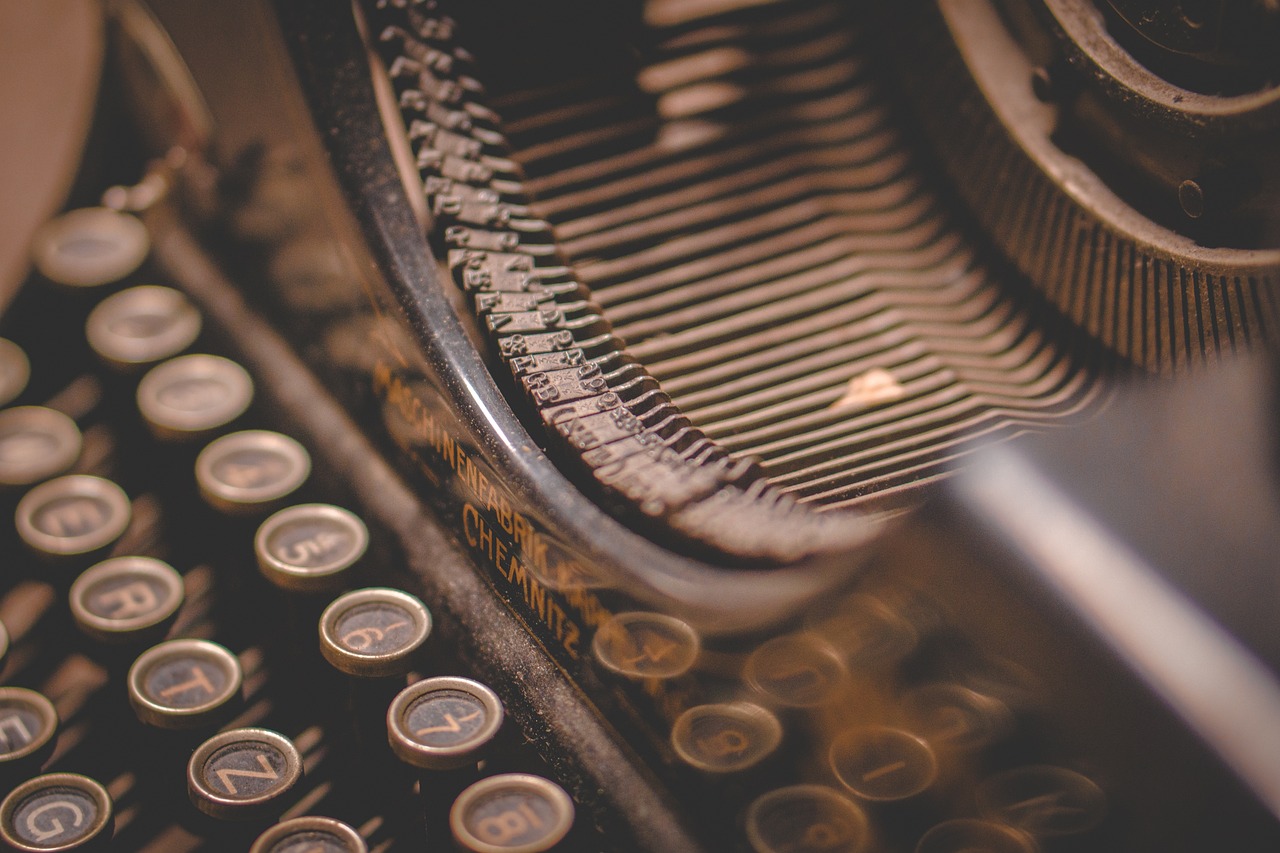 A close up of a typewriter showing some of the keys and the hammers to illustrate the search for new writers