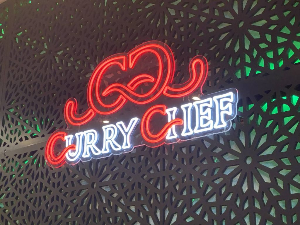 a neon sign on a wall saying Curry Chef