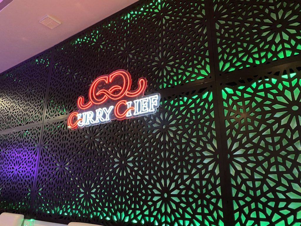 a neon sign on a wall saying Curry Chef