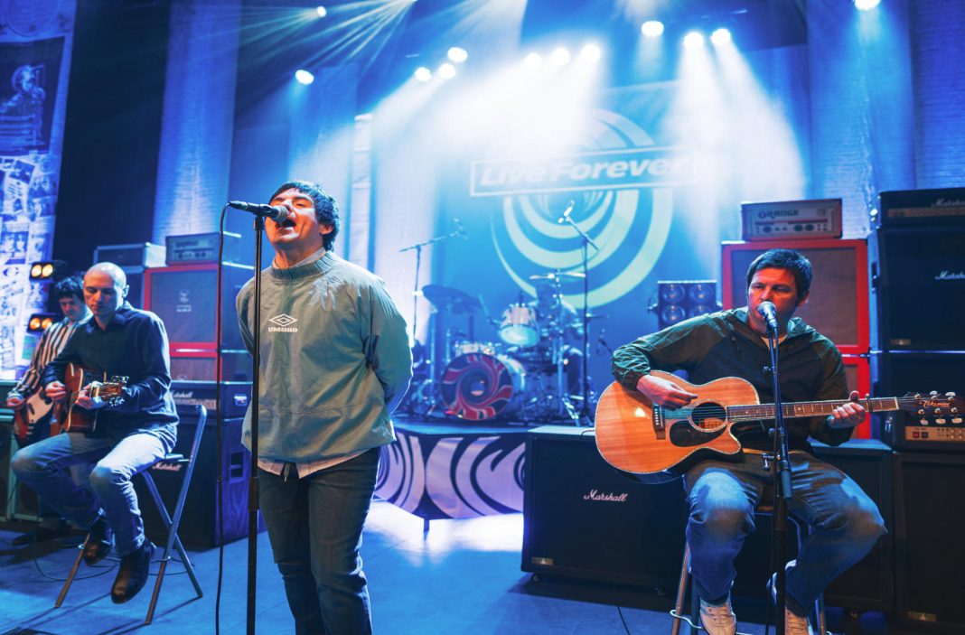 Live Forever came to The Hexagon and celebrated the music of Oasis - the band are performing on stage. On each side of the image a musician is playing a guitar, in the middle is a singer