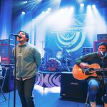 Live Forever came to The Hexagon and celebrated the music of Oasis - the band are performing on stage. On each side of the image a musician is playing a guitar, in the middle is a singer