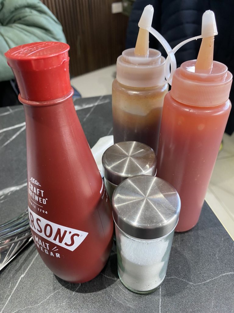 Condiments at Woodley Café including vinegar, salt and pepper, brown sauce and tomato ketchup