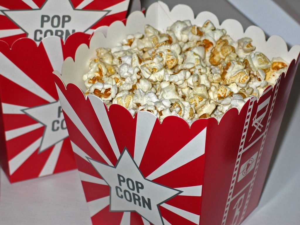 a red and white striped container with popcorn, something people can eat when watching a film