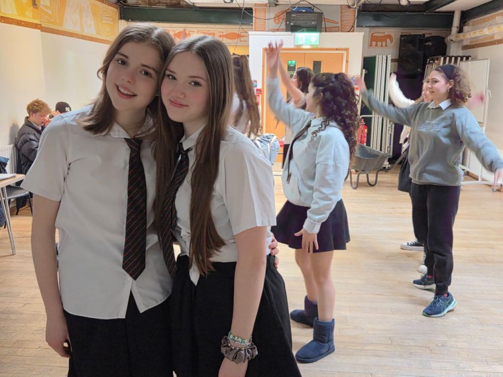 Mia and Grace, who play Willow and Taylor in Berzerk Productions National Theatre Connections show The Company of Trees - cast members rehearse a scene in the background while Mia and Grace are in the foreground