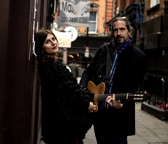 Irene Serra and Luca Boscagin standing in a street. Luca has a guitar around his shoulders. They perform The Great British Songbook