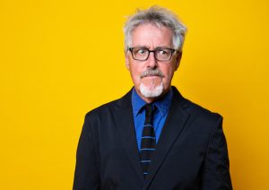 Griff Rhys Jones against a yellow background