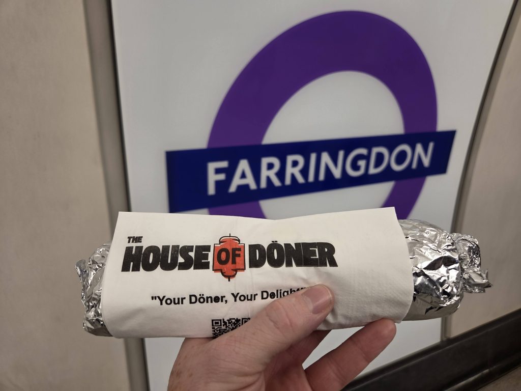 A wrapped House of Doner kebab next to a tube station sign that reads Farringdon