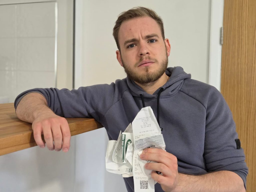 Ben Lewis holding some receipts and leaning against a counter