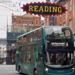 Reading Buses emerald bus going through Reading Town Centre. it is passing under a recreation of the Reading festival logo