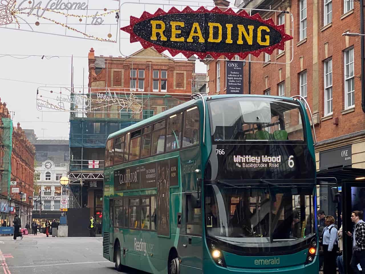 Reading Buses emerald bus going through Reading Town Centre. it is passing under a recreation of the Reading festival logo