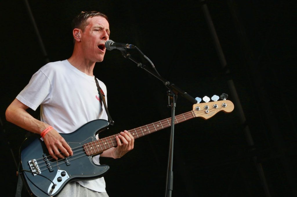 A man singing on stage into a microphone and playing a guitar