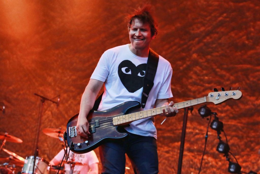 A man in a white T-shirt with an electric guitar