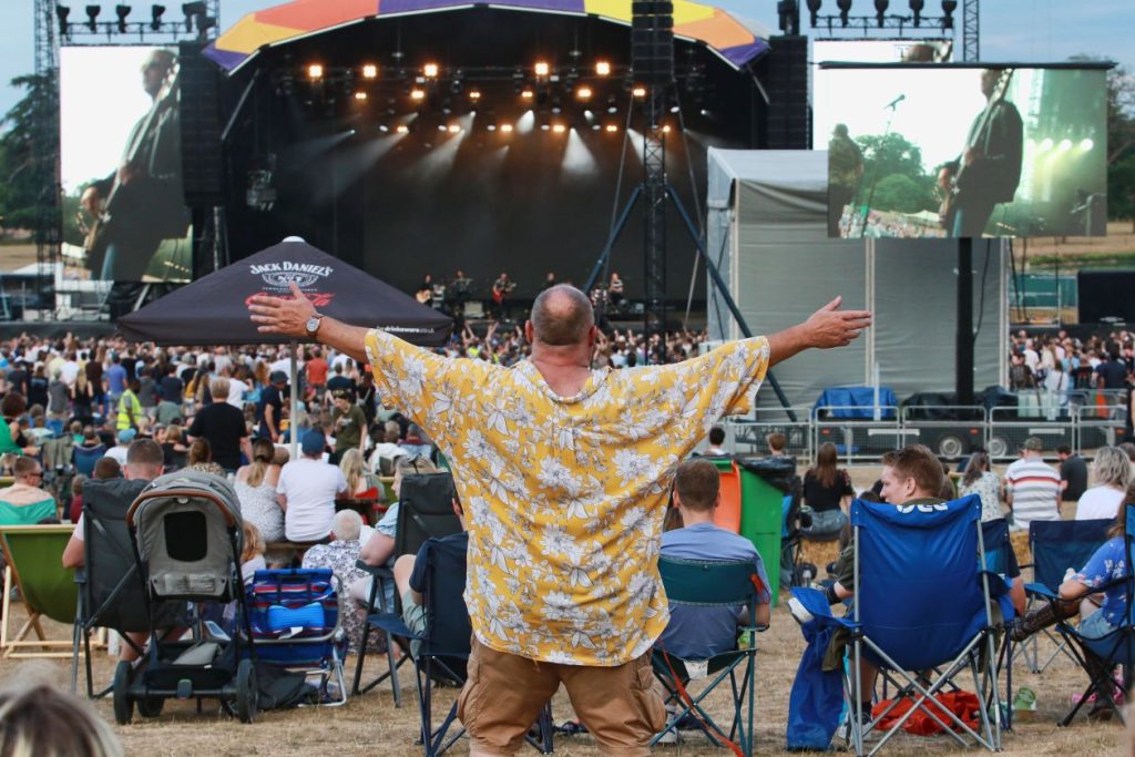 A music fan holds his arms aloft while enjoying the outdoor festival Englefield Live