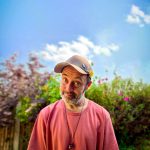 The artist known as Beans on Toast standing outside. He is wearing a baseball cap and has he head at a jaunty angle