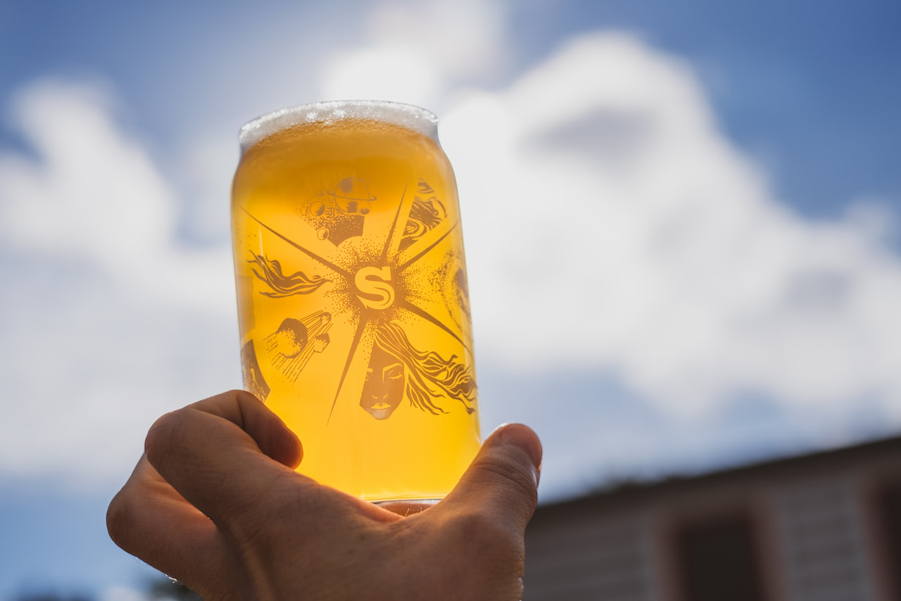 A glass of Lumina beer held up to the sunlight