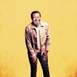 Stephen K Amos against a yellow background