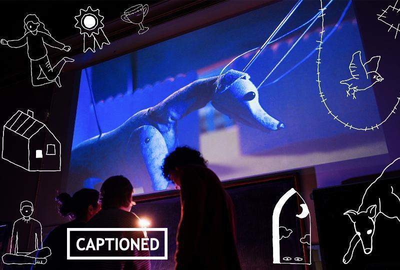 A puppet dog. A sign says captioned