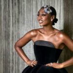 Beverley Knight standing with her hands on her hips wearing a black dress, smiling