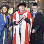 The University of Reading presented an honorary degree to Phil Creighton (pictured centre). All three people are wearing ceremonial robes for an academic institution.