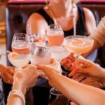 A close-up view of a group of people toasting with an assortment of colourful cocktails and drinks in glassware during the upcoming Reading Cocktail Week