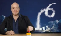 Andy Parsons pushing a red button with a rocket launch behind him