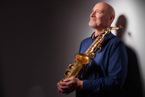 Simon Bates looking up, holding a saxophone in his hands