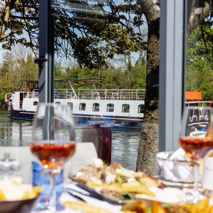 A dining table set up at Mediterranevm bray - the background is a passenger boat heading along the River Thames
