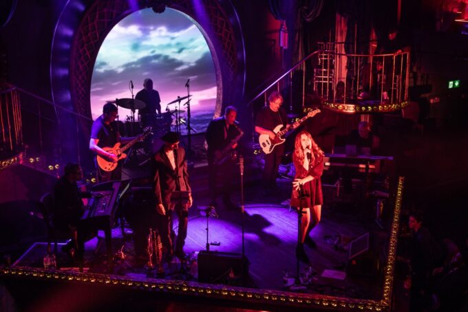 The Van Morrison Alumni Band performing live on stage with brass instruments and vocalists.